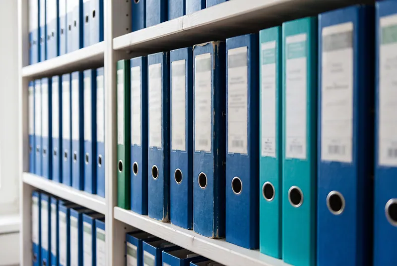 Eine Wand mit blauen Ordnern im Büro von Kneubühler Finanz